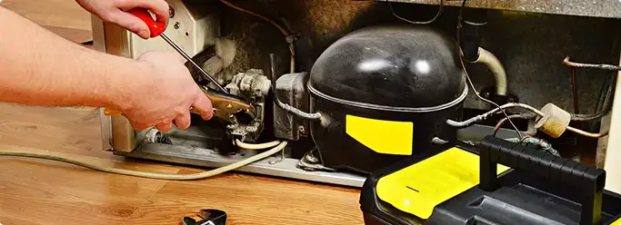 Refrigerator repair technician fixing the compressor and wiring in South Saint Paul, MN
