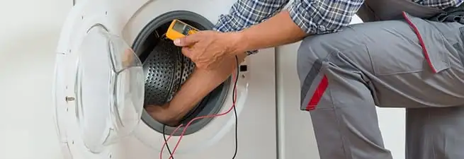 Dryer repair technician inspecting and repairing a clothes dryer in Minneapolis, MN