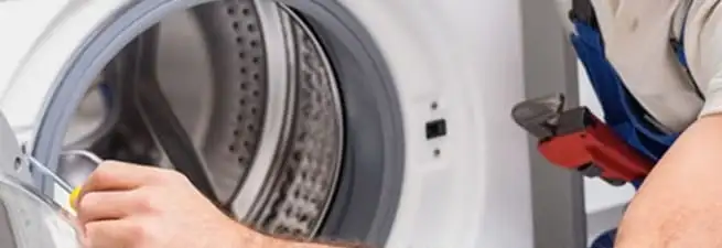 Appliance technician repairing a clothes dryer drum and internal parts in Minneapolis, MN