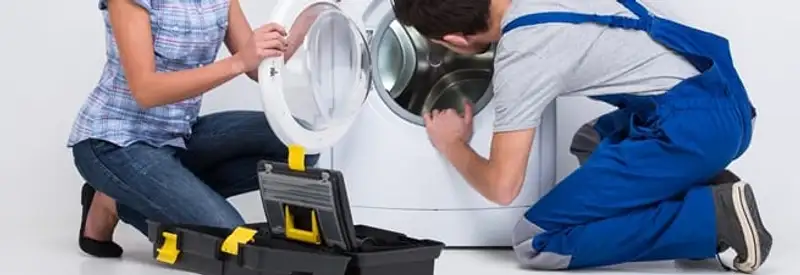 Washer repair technician inspecting a front-load washing machine with tools in Minneapolis, MN