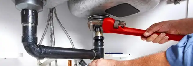 Garbage disposal repair technician tightening the sink drain and disposal connection in Minneapolis, MN