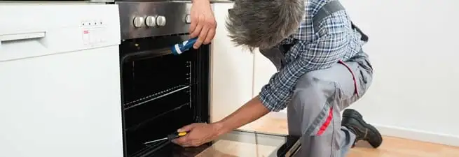 Oven repair technician inspecting and servicing an electric oven in Minneapolis, MN