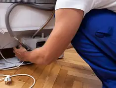 Appliance repair technician fixing refrigerator water line and connections in Minneapolis, MN