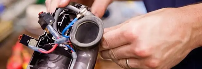 Vacuum repair technician reconnecting wiring and components in Minneapolis, MN