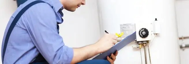 Water heater repair technician inspecting the unit and recording service notes in Minneapolis, MN
